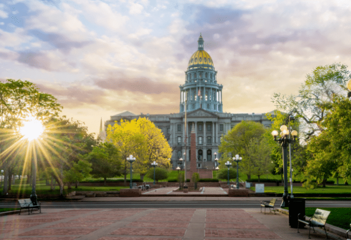 The Colorado State Capital Building with a sun burst and clouds
