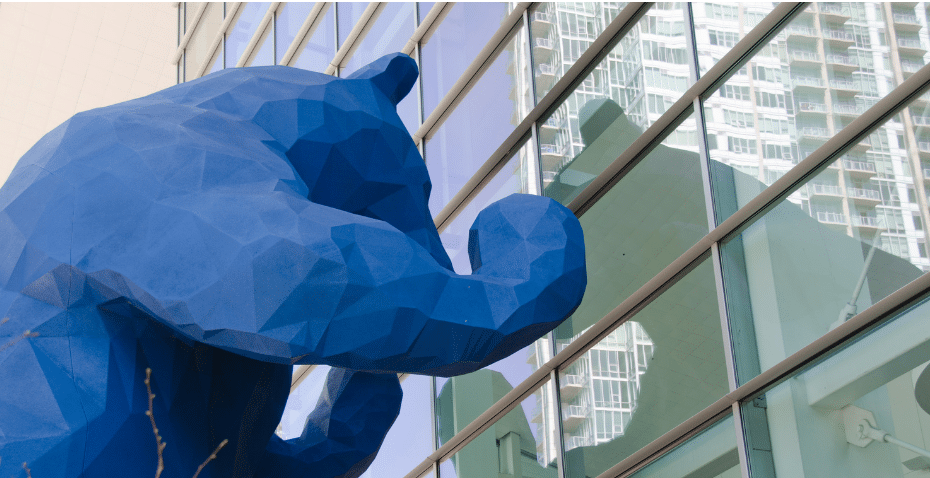 Iconic 40-foot blue bear standing peering into the Denver Convention Center.