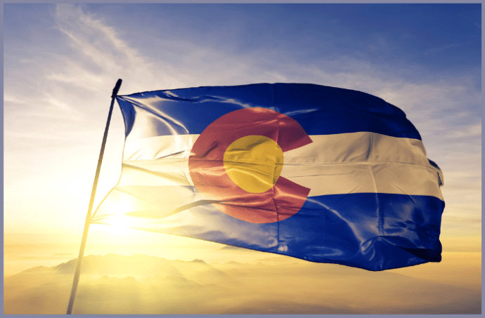 Colorado state flag with the sun setting over the mountains